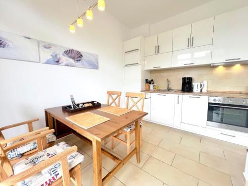 a kitchen with white cabinets and a wooden table at Ferienwohnung Meerblick in Juliusruh