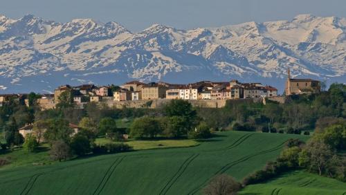a town on top of a hill with snow covered mountains at 85 m2 de plain-pied dans maison confortable avec vue sur la vallée et les Pyrénées ariégeoises, grande terrasse avec barbecue et parking gratuit in Castéras