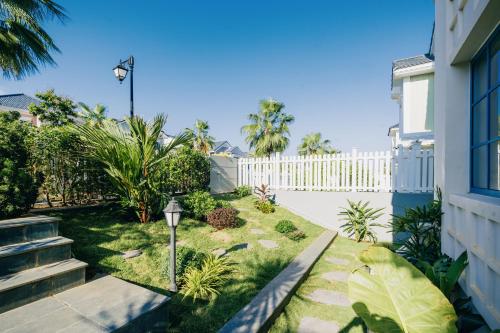 a backyard with a white fence and a yard at DT Retreat - Biệt thự nguyên căn - 3 Phòng ngủ - Novaworld Phan Thiết in Phan Thiet