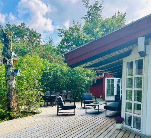 a wooden deck with chairs and tables and a building at Togetherness, Coziness & Magical Great Belt View in Tranekær