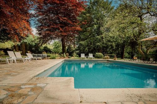 a swimming pool in a yard with chairs and trees at Relais M in Frasnes-lez-Anvaing