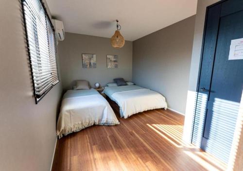 two beds in a room with wood floors at HAKATA TERRACE -akari- - Vacation STAY 12420 in Fukuoka