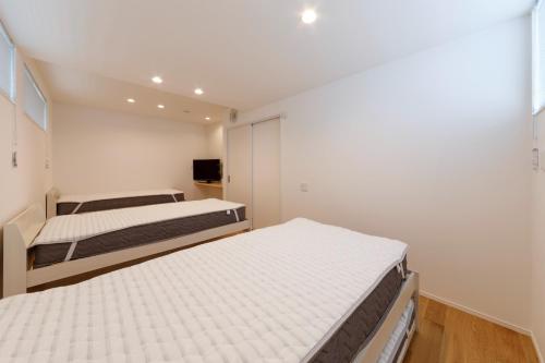 two beds in a room with white walls at SEASIDE TERRACE SUN - Vacation STAY 12430 in Numazu