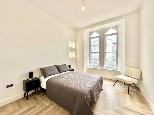 ein Schlafzimmer mit einem Bett, einem Stuhl und einem Fenster in der Unterkunft Bath House luxury Apartments in Ilfracombe