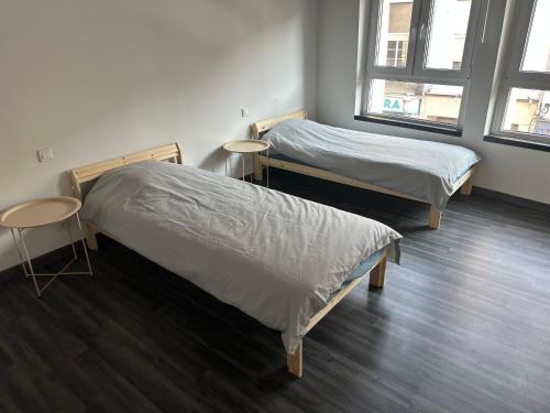 two beds in a room with two windows at Bel appartement lumineux in Saint-Avold