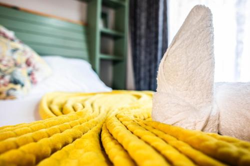 a bed with yellow sheets and a roll of paper on it at Gorgeous Gecko Guesthouse in Modimolle