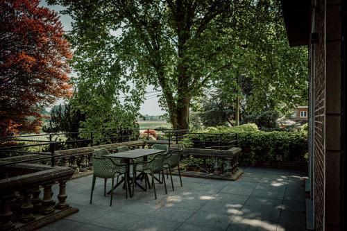 a table and chairs on a patio under a tree at Relais M in Frasnes-lez-Anvaing
