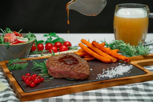 a steak on a cutting board with carrots and a drink at Malinowy Dwór Hotel Medical SPA in Świeradów-Zdrój