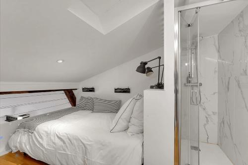 a white bedroom with a bed and a shower at Les Relais du Capitole - Appartements d'hôtes in Toulouse