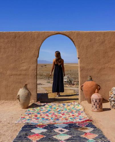 a woman standing in an archway with a rug at Caravansérail Agafay by Dar Inacamp in El Mjed