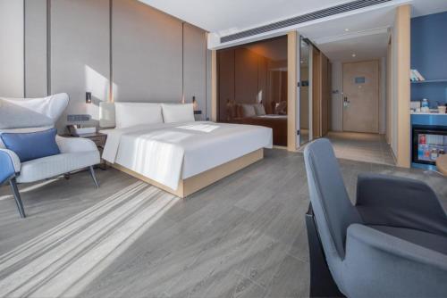 Atour Hotel Xuzhou Chuangtuo Aofan Mining University في سوزهو: غرفة نوم بها سرير وأريكة وكرسي