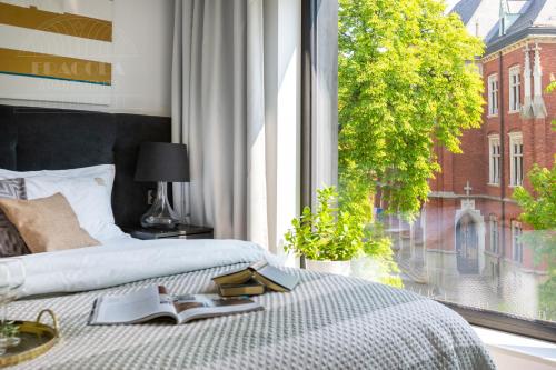 a bedroom with a bed and a window with a book on it at Modern View of Planty Park in Kraków