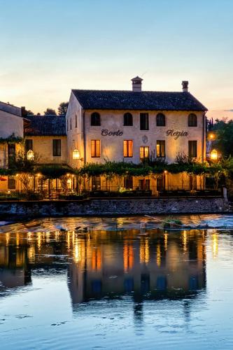a building sitting next to a body of water at Corte Regia Relais & Spa in Valeggio sul Mincio