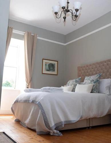 a bedroom with a large white bed with a chandelier at Hill House Cashel in Cashel