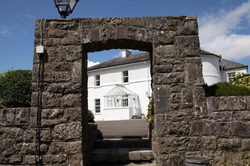 an arch in a stone wall in front of a white house at Hill House Cashel in Cashel