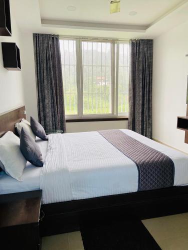 a bedroom with a large bed with pillows at Cool breeze view Homestay in Madikeri