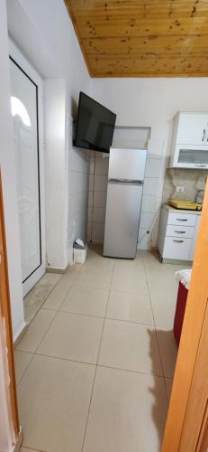 eine Küche mit Kühlschrank und einem an der Wand befestigten Fernseher. in der Unterkunft apartments sofie 1 in Ksamil
