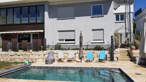 a swimming pool with chairs and umbrellas in front of a house at glüxnest in Bernstadt