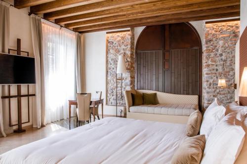 a bedroom with a large white bed and a couch at Corte Regia Relais & Spa in Valeggio sul Mincio