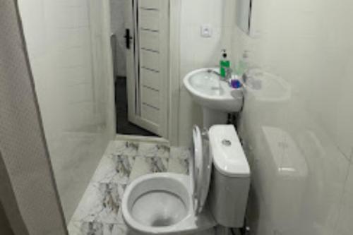 a white bathroom with a toilet and a sink at Lotus Hotel in Yakkasaray