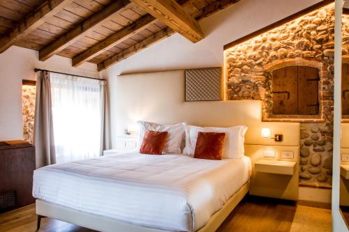a bedroom with a white bed with a stone wall at Corte Regia Relais & Spa in Valeggio sul Mincio