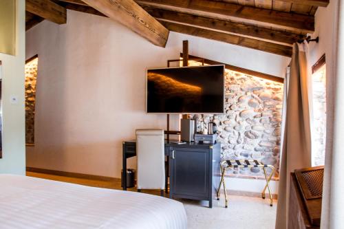 a bedroom with a bed and a tv on a wall at Corte Regia Relais & Spa in Valeggio sul Mincio