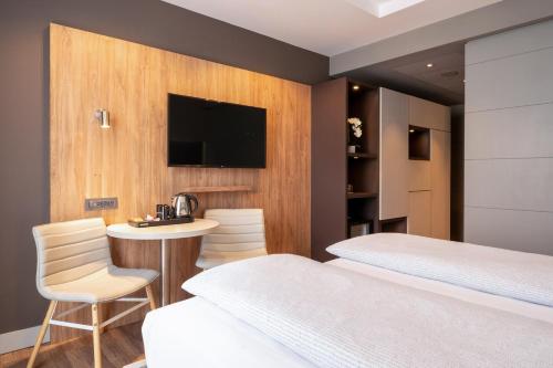 a room with two beds and a table and a tv at INNSiDE by Meliá Prague Old Town in Prague
