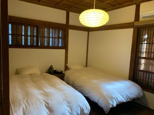 two beds in a room with windows and a chandelier at uminca - Vacation STAY 09850v in Numazu