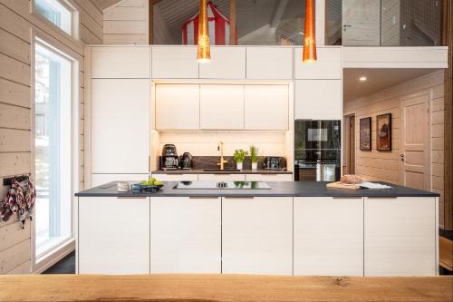 a kitchen with white cabinets and a black counter top at Stay North - Skadi Lodge in Ylläs
