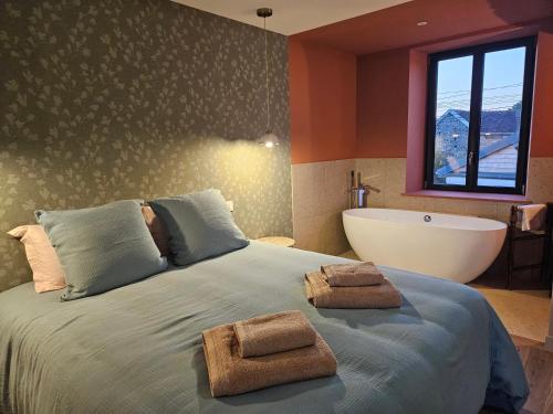 a bedroom with a bed with a tub and a large bed with towels at La Maison des Chouettes in Maisons-lès-Chaource