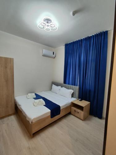 a bedroom with a bed and a blue curtain at Lotus Hotel in Yakkasaray