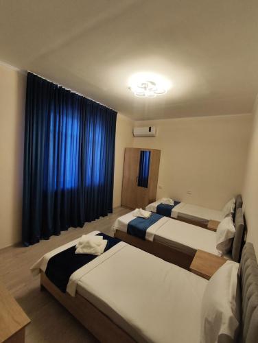 two beds in a room with blue curtains at Lotus Hotel in Yakkasaray