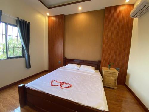 a bedroom with a large white bed with a red necklace on it at Khách Sạn Thái Trâm in Cao Lãnh