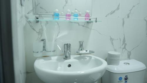 a white bathroom with a sink and a toilet at Lotus Hotel in Yakkasaray