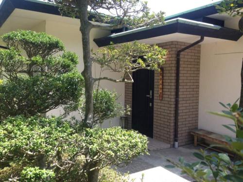 a house with a black door and some trees at HOTSPRING HOUSE IN KOWAKUDANI - Vacation STAY 14262v in Ashinoyu