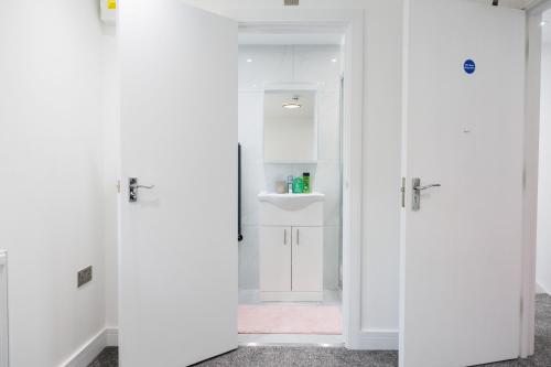 a bathroom with white doors and a sink at 45GR Dreams Unlimited Contractor Home in Harrow in Harrow