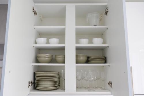 a white cabinet filled with dishes and glasses at 45GR Dreams Unlimited Contractor Home in Harrow in Harrow