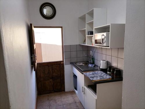 a small kitchen with a counter and a clock on the wall at Gorgeous Gecko Guesthouse in Modimolle