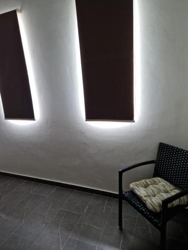 a black chair sitting in a room with two windows at Casa Andries Montanja Rey in Willemstad