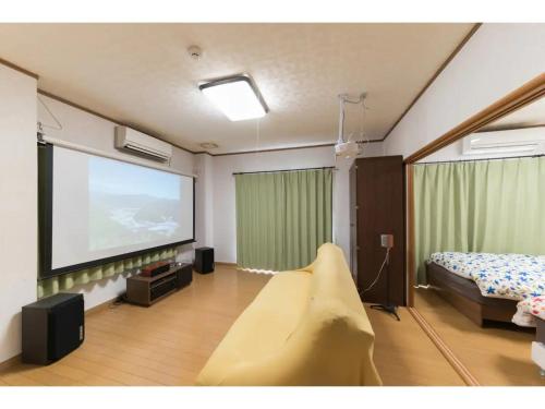 a room with a large screen with a bed and a tv at Yado wa Good Rich - Vacation STAY 30399v in Tokushima