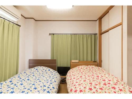 a bedroom with two beds and green curtains at Yado wa Good Rich - Vacation STAY 30399v in Tokushima