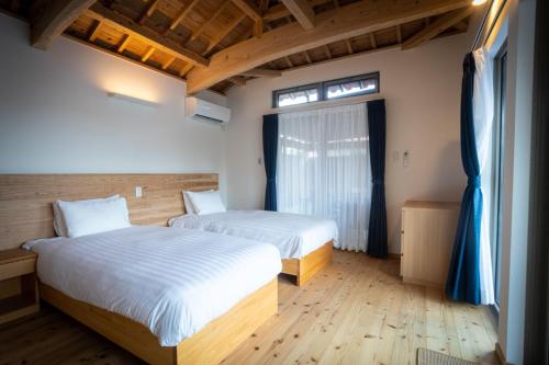 two beds in a room with wooden floors and windows at Villa Muse Okinawa- Vacation STAY 43827v in Nago