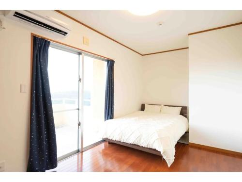 a bedroom with a bed and a large window at Stardust Motobu - Vacation STAY 45756v in Motobu