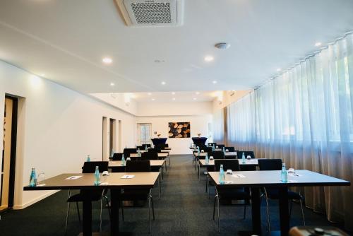 a room with tables and chairs in a room with windows at Arthotel Ambassador Wiesbaden - FREE PARKING in Wiesbaden