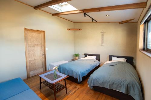 two beds in a room with a couch and a table at CANOA GUEST HOUSE A room - Vacation STAY 50937v in Ikeda