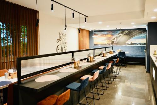 a restaurant with a long bar with chairs and tables at Arthotel Ambassador Wiesbaden - FREE PARKING in Wiesbaden