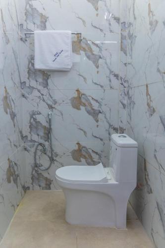a white toilet in a bathroom with a marble wall at Pavan Vela Grand in Dindigul