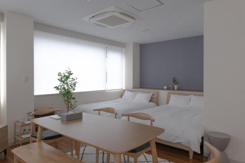 ein Schlafzimmer mit zwei Betten und einem Tisch und einem Tisch und Stühlen in der Unterkunft RIVER VILLAS HIROSHIMA - Vacation STAY 24194v in Hiroshima