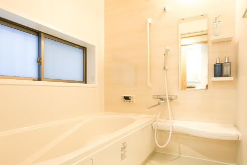 a white bathroom with a tub and a window at NAGI - Vacation STAY 41896v in Nanjo