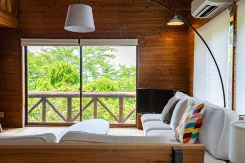 ein Wohnzimmer mit Couch und großem Fenster in der Unterkunft Cottage Coliberty - Vacation STAY 60526v in Anan